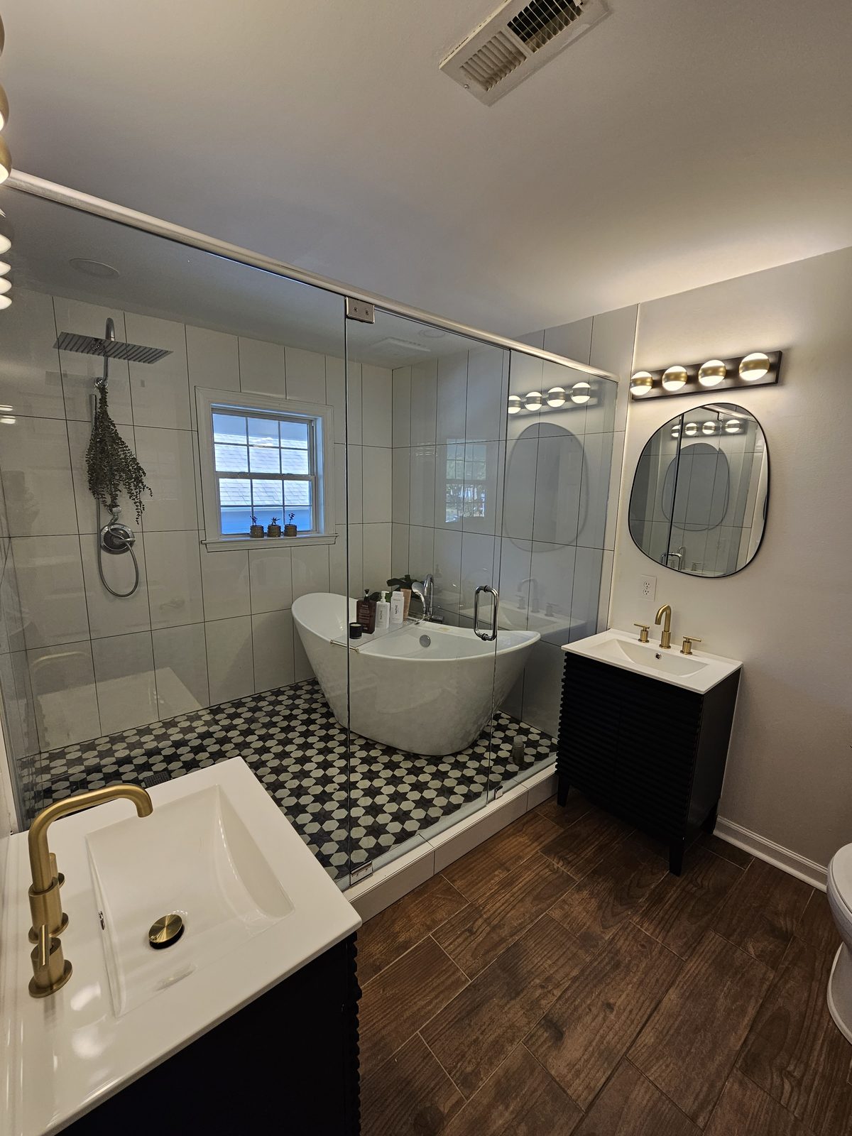 A freestanding tub, glass shower and black and white mosaic floor