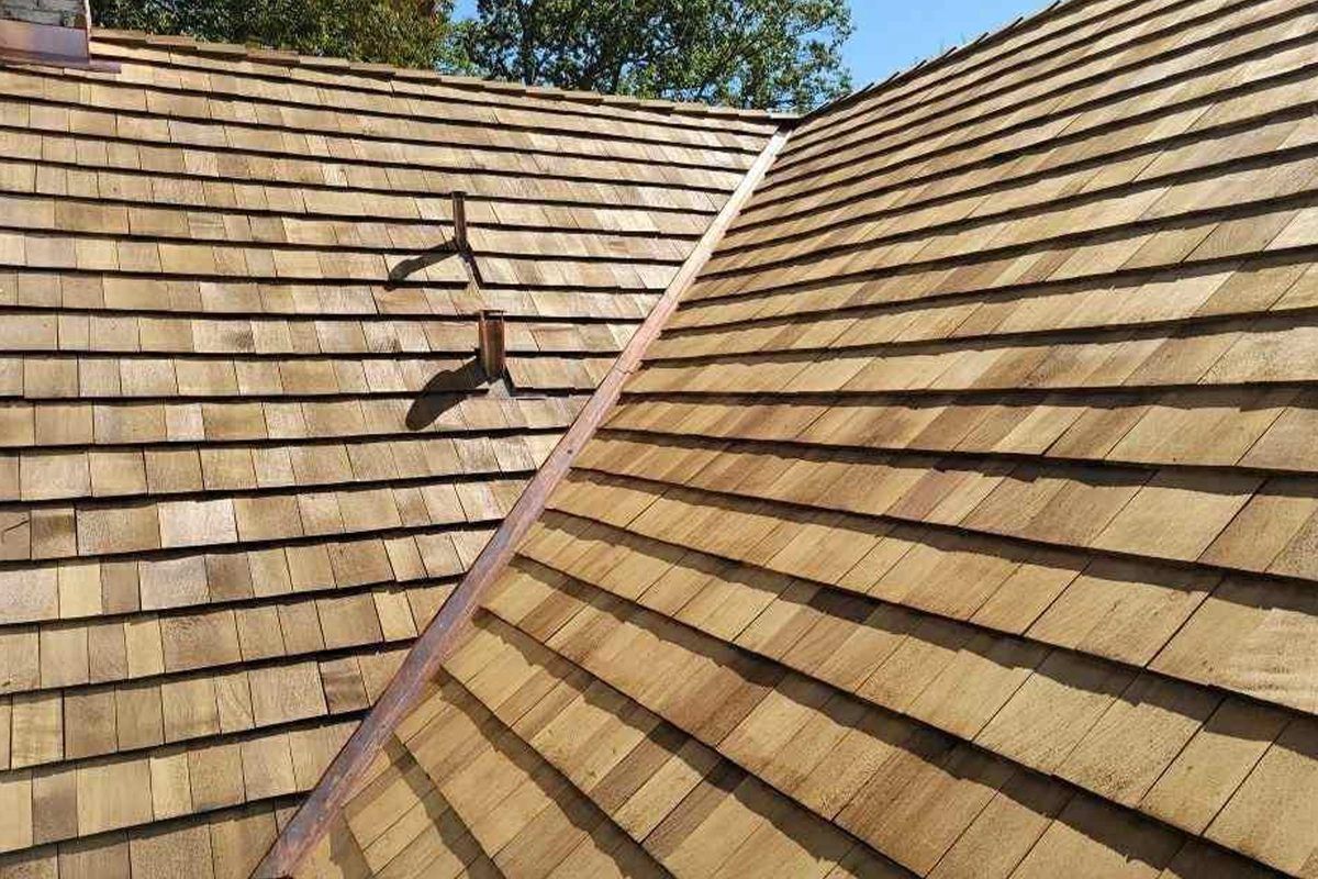 New cedar shake roof with a valley and vent against blue sky
