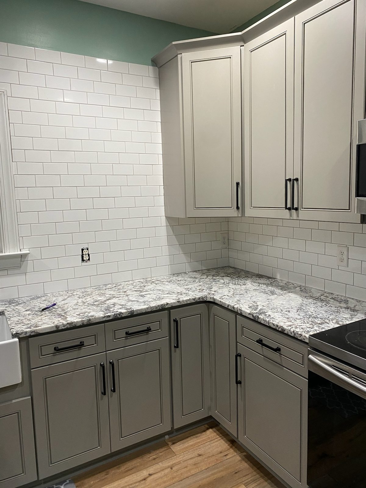 Gray cabinets with a white subway tile backsplash and granite countertops