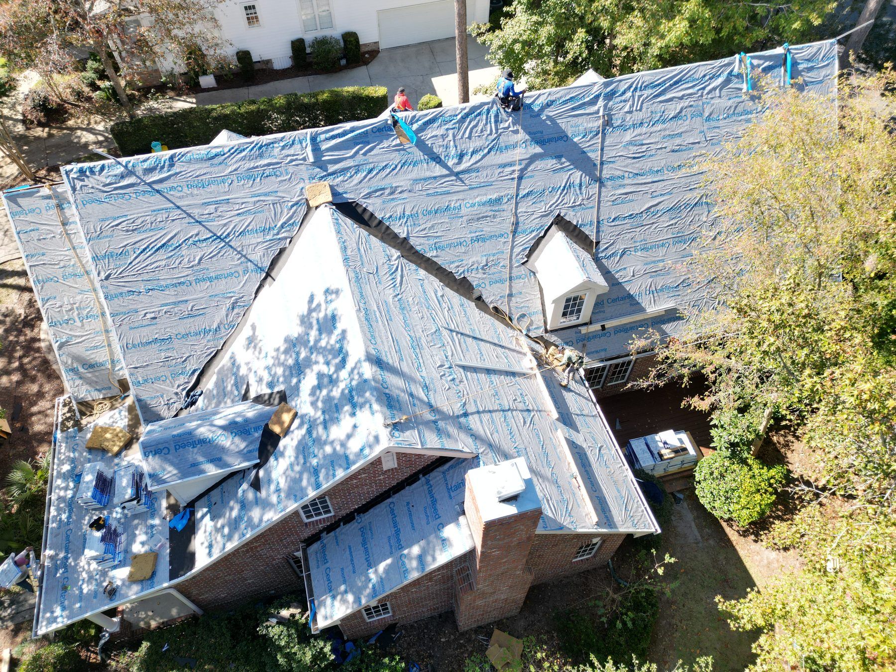 A large home with dormers, its roof covered in underlayment during a TPC replacement