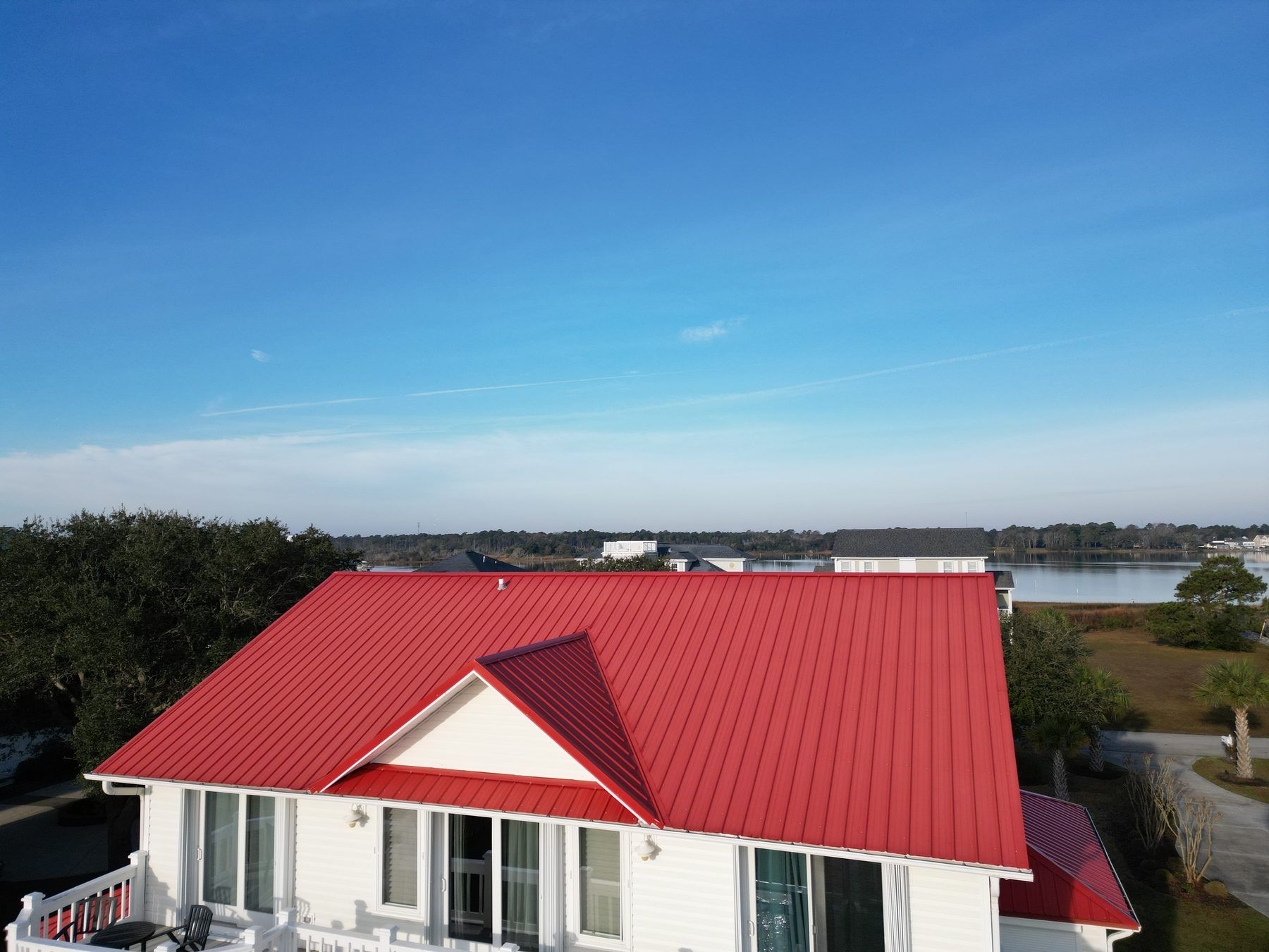Red metal roof gable end with a water view