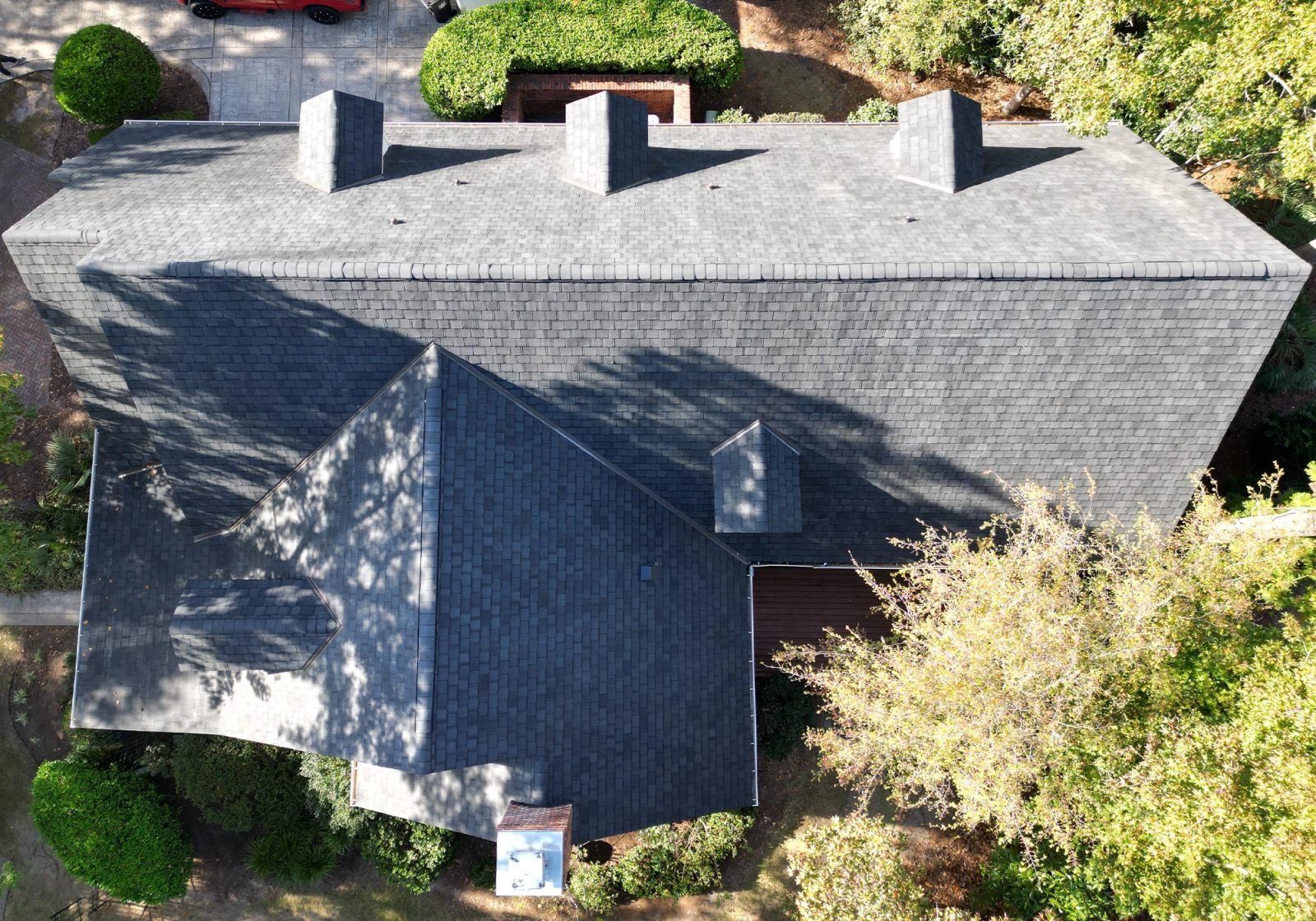 Large home with dark architectural shingles and dormers, from the air