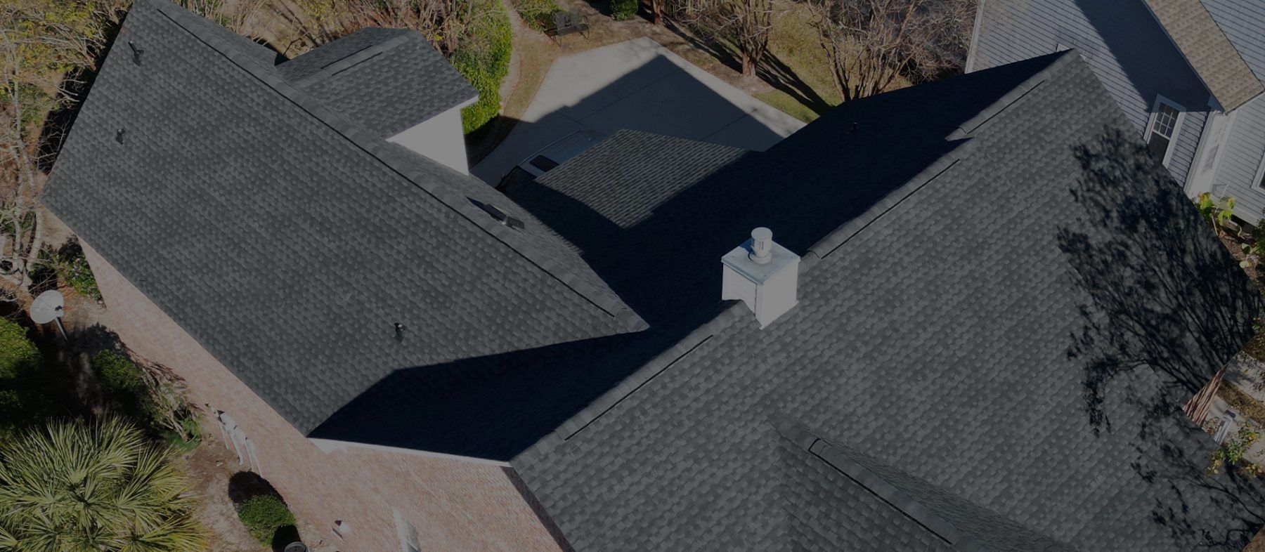 Dark charcoal shingle roof from above with a white chimney