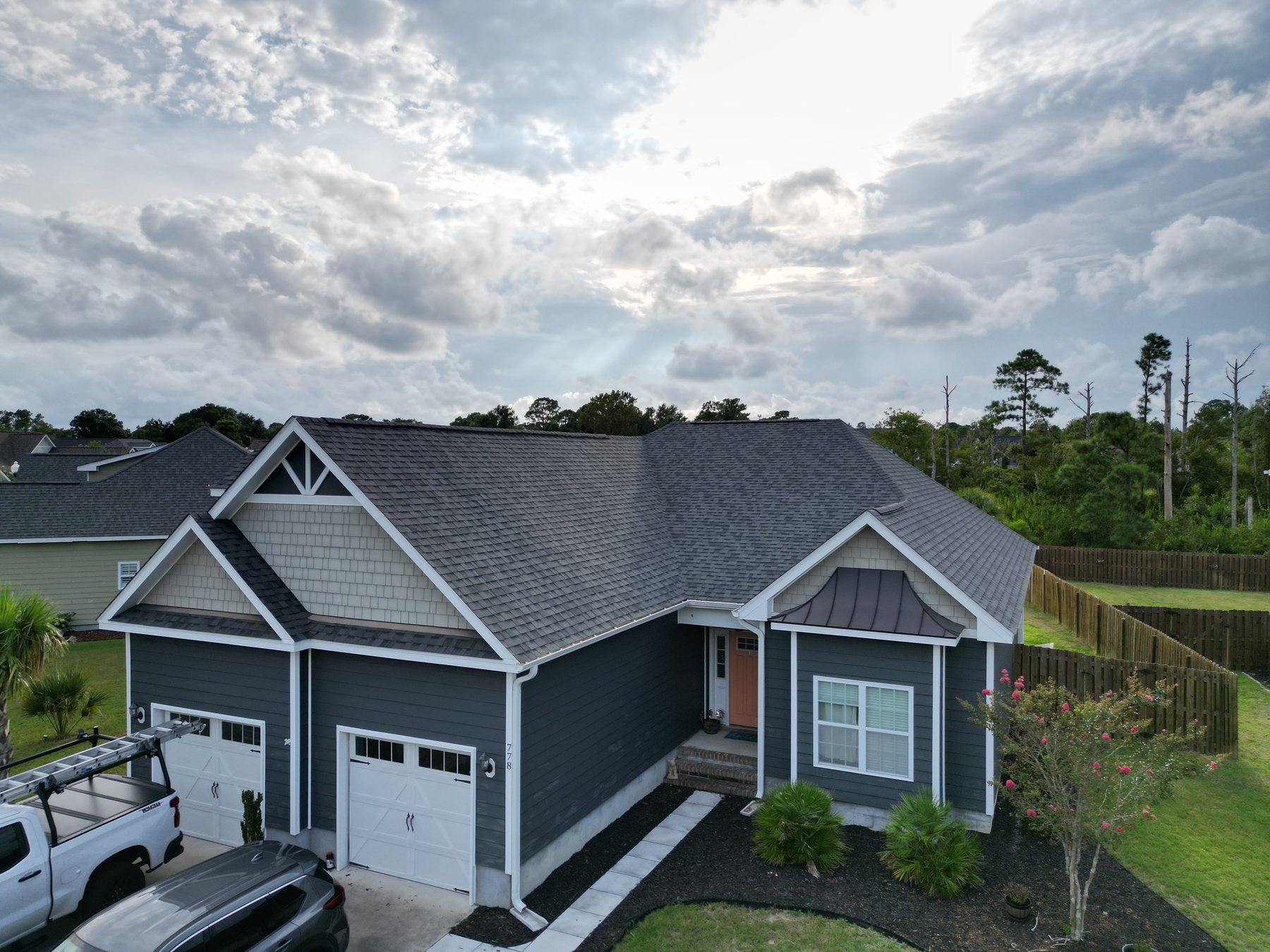 Blue-grey home with a new gray shingle roof under a big cloudy sky